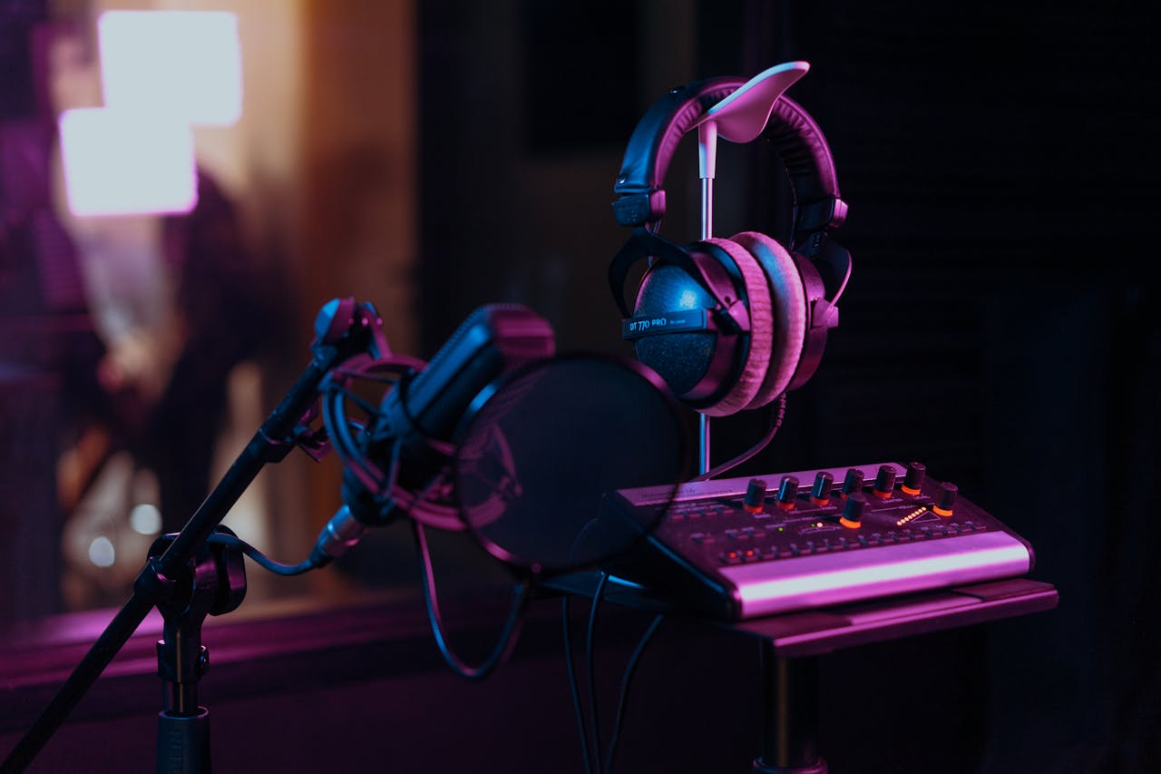 High-quality audio recording studio setup with a microphone, headphones, and mixer board in dim lighting.